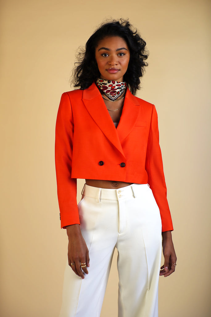 model with silk scarf wrapped around neck and bright orange double breasted cropped blazer